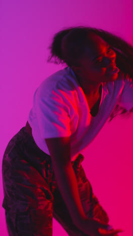 Vertical-Video-Studio-Shot-Of-Young-Woman-Dancer-Dancing-Against-Blue-And-Pink-Lit-Background